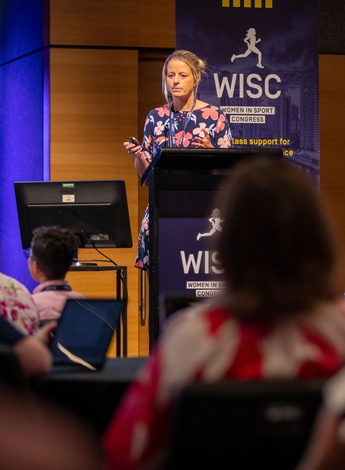 The image is of Brooke Patterson presenting at the Women in Sport Congress. 